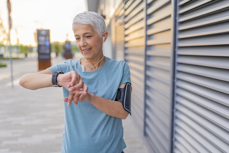 Mature Runner Checking Smart Watch. Checking Fitness Statistics On Smart Watch. Athletic mature woman monitoring her running performance on smartwatch